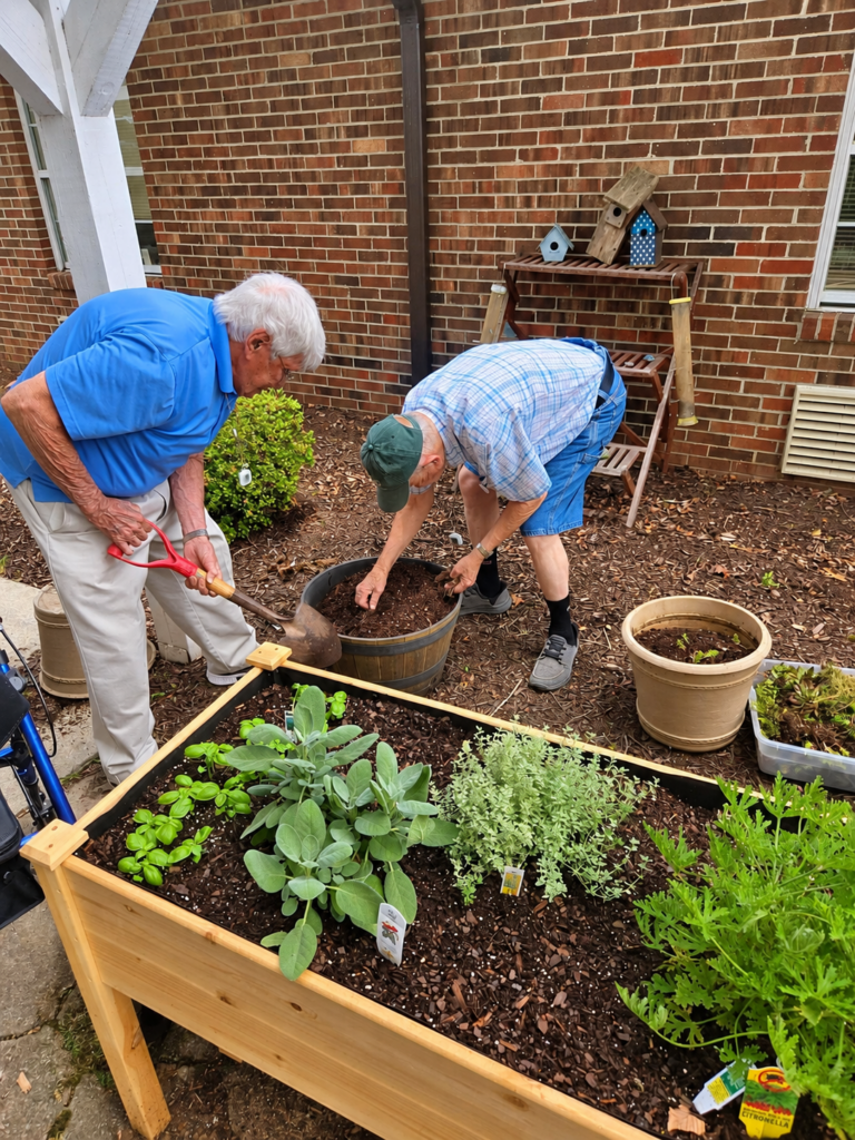 Two residents tending a raised garden bed at The Woodland in Farmville, Virginia